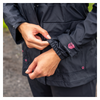 Person adjusting the sleeve of a navy jacket with a visible brand logo.