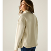 A woman wearing a cream-colored fleece pullover jacket, shown from a side-back angle against a plain light beige studio background.
