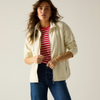 A woman modeling a cream zip-up hoodie over a red and white striped t-shirt and blue jeans, photographed against a solid light gray studio background.
