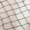 A close-up of a black chain-link safety net draped over a light beige or off-white background.