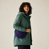 Woman wearing a green jacket with a purple bag on a beige background