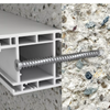 Close-up of a white aluminum or vinyl wall trim profile with a long silver screw fastener inserted into a textured concrete or stone wall.