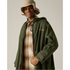 A man wearing an olive green hooded raincoat over a brown and beige plaid flannel shirt, paired with a beige bucket hat, against a solid light gray background.