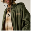 A close-up of a person wearing an olive green hooded jacket with a visible Batta Outdoors logo on the chest, layered over a tan plaid shirt and hat.