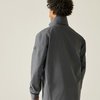 A man shown from the back wearing a grey shell jacket photographed against a plain light beige studio background.