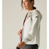 A woman wearing a light gray hooded athletic jacket with pink and black side stripes, photographed against a plain light gray studio background.