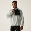 Man wearing a gray and black pullover with a visible brand logo on a plain background
