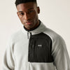 Man wearing a gray and black fleece jacket with a visible brand logo on a white background