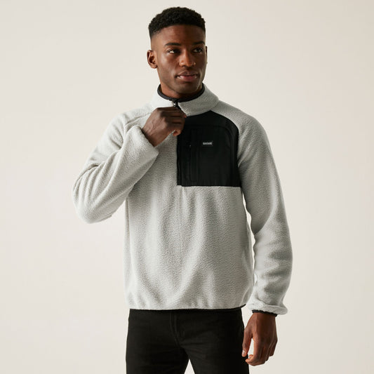 Man wearing a gray and black pullover with a visible brand logo on a plain background