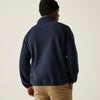 Person wearing a navy blue fleece jacket and beige pants on a plain background