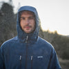 Man wearing a blue raincoat in a rainy outdoor setting