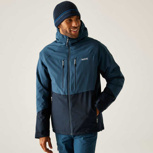 Man wearing a blue and black jacket with a hood on a light gray background