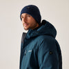 Man wearing a blue jacket and beanie against a plain background