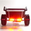 Rear view of a black utility trailer with dual wheels and bright amber LED lights illuminated, set against a plain white studio background.
