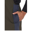 Close-up of a person wearing an olive green and navy blue work apron, with a hand inserted into a side pocket.