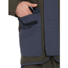 Close-up of a person wearing a utility jacket with a large front flap pocket and a hand tucked into the pocket, shown against a plain white background.