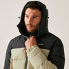 Man wearing a black and beige puffer jacket with a hood on a plain background