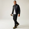 Man wearing a black jacket and pants with hiking boots, holding a phone, on a white background