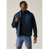 A man wearing a dark blue quilted puffer vest over a navy quarter-zip pullover, paired with light blue shorts, shown against a plain light beige studio background.