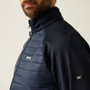 Person wearing a black jacket with a quilted blue section on a neutral background