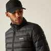Man wearing a black puffer jacket and cap with a visible brand logo on a neutral background