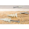 White plastic wall anchors with silver metal screws displayed on a wood chip surface.