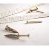 Four brass wall anchors and matching screws arranged on a light gray textured surface.