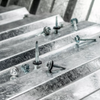Close-up of metal roofing screws and fasteners placed on galvanized steel ridges.