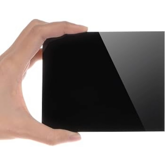 A hand holding a rectangular black glossy panel or card against a plain white background.