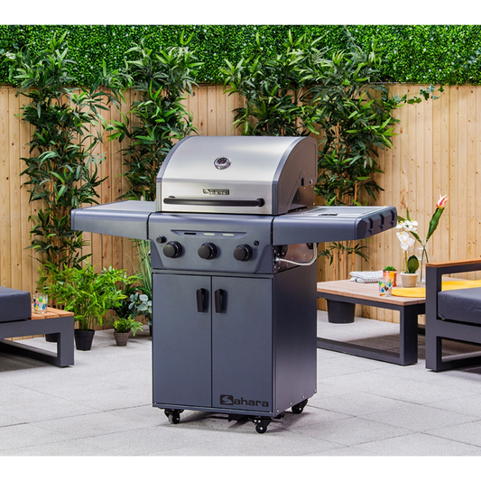 Gray barbecue grill on a patio with greenery and outdoor furniture in the background