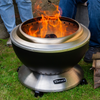Metal fire pit with flames on a grassy area