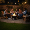 Group of people sitting around a fire pit in a backyard at night.