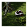 Robotic lawn mower on a grassy area with a tree trunk in the background