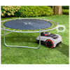 Robotic lawn mower next to a trampoline on grass