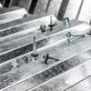 Close-up of metal roofing screws and fasteners arranged on galvanized steel ridges, with a shallow depth of field.