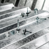 Close-up of galvanized metal roofing or siding panels with several metal screws and fasteners placed on the surface.
