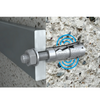 A close-up of a metal wall anchor bolt with a nut and washer, shown mounted against a textured concrete wall. The anchor body has visible branding and a blue concentric circle graphic near it.
