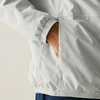 Close-up of a person wearing a light gray heathered lightweight jacket, showing the sleeve with an elastic cuff, a side pocket, and a hand tucked inside.