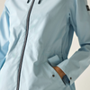 Close-up of a person wearing a light off-white zip-up jacket, showing a hand reaching into a side zip pocket. The jacket has a thin dark stripe running vertically along the front zipper and a small pink accent near the shoulder.
