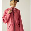 A woman wearing a pink hooded rain jacket with a black front zipper and white drawstrings, paired with a dark cap, photographed against a plain light gray studio background.