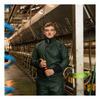Man in green raincoat holding a tool inside a large industrial setting