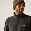 Man wearing a dark gray fleece jacket with a brand logo and a green beanie against a plain background