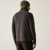 Person wearing a dark gray fleece jacket and green beanie on a light background