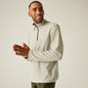 Man wearing a light gray pullover with a brand logo on a beige background