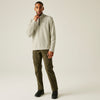 Man wearing a light gray hoodie and olive green pants on a beige background