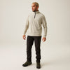 Man wearing a beige pullover with a black zipper and black pants on a white background