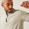 Man wearing a beige fleece pullover with a brand logo on a light background