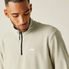 Man wearing a beige fleece pullover with a brand logo on a plain background