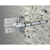 A stainless steel wall anchor bolt with a flat mounting plate and hex nut, shown installed against a textured concrete wall.