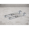 Two silver metal threaded wall anchors with nuts and washers, placed on a light gray concrete surface.